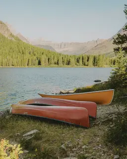 Canoes pulled up on the shore of a mountain lake.