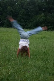 Someone mid-cartwheel in a field of tall grass.